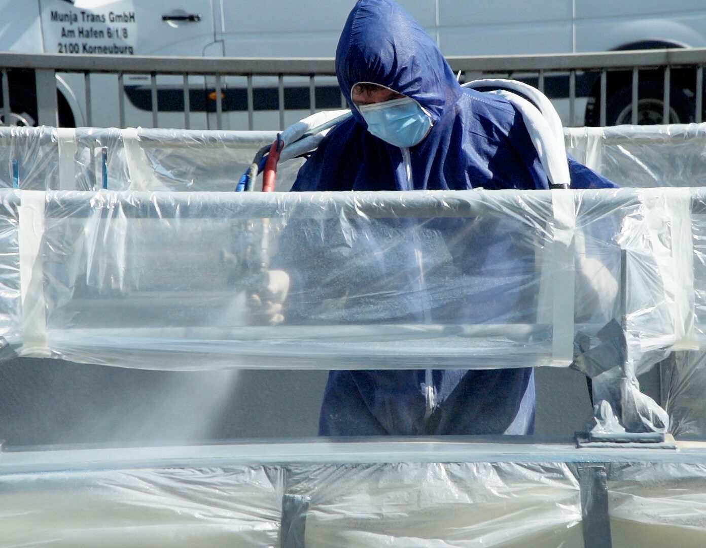 A man in a blue suit spraying a Polyflex container.
