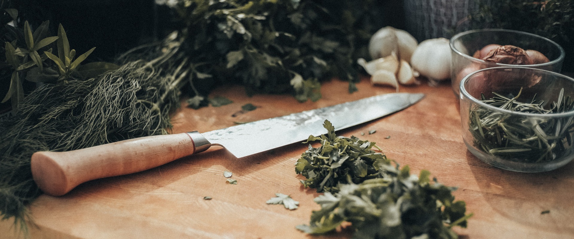 A knife and herbs on an Eggenhof cutting board.