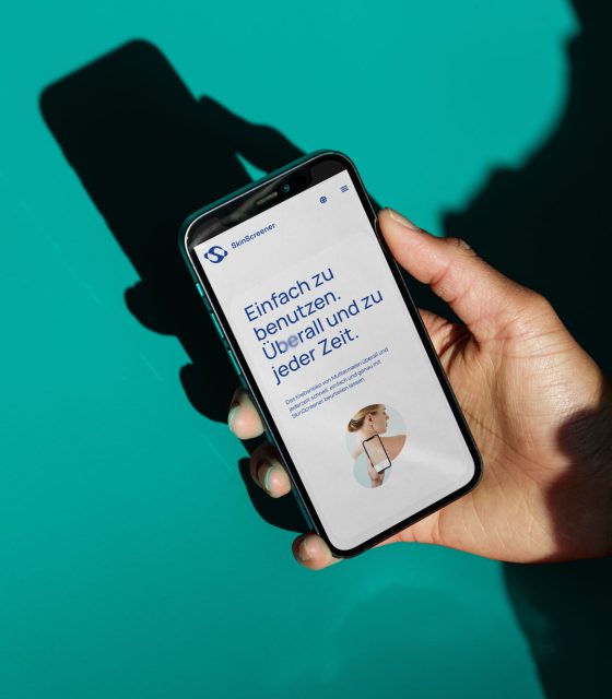 A person holding up a phone with a SkinScreener app on it.