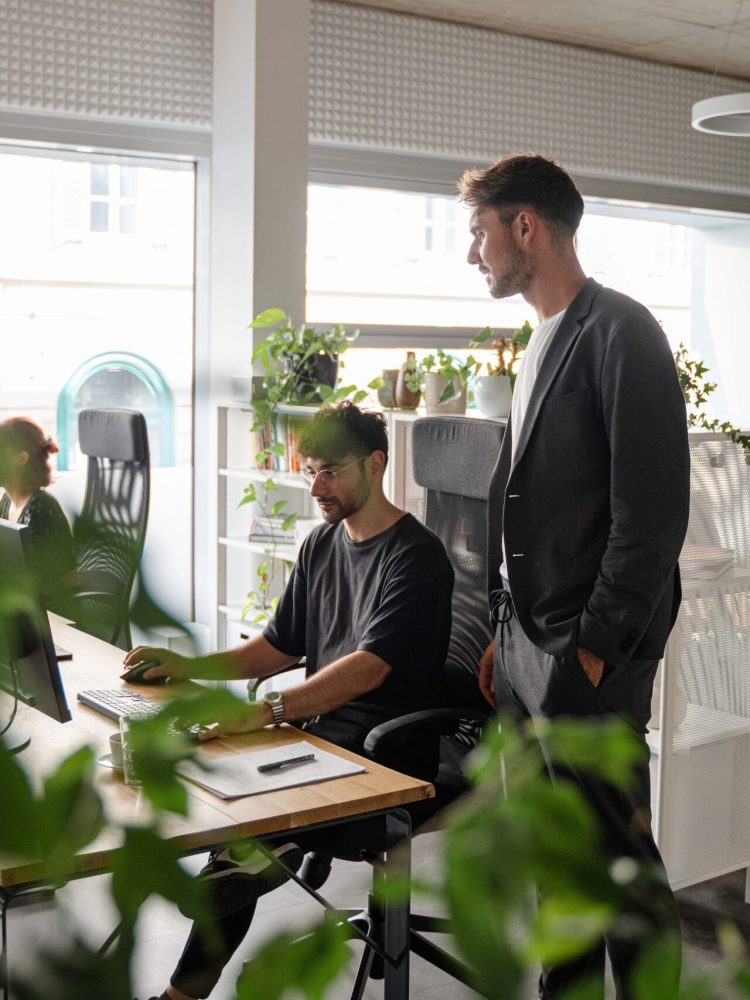A group of people working in an office with plants.