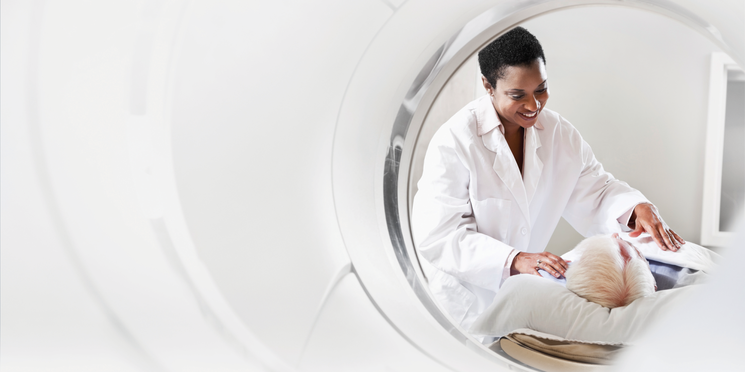 A woman in a white coat is looking at a mri machine.