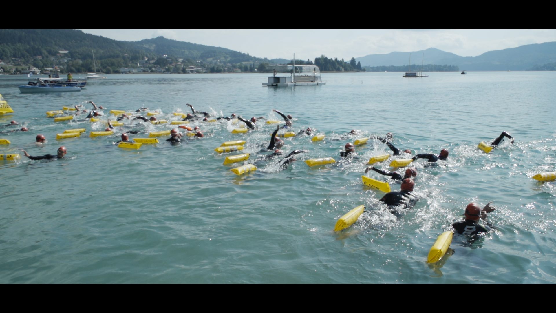 Eine Gruppe von Menschen schwimmt mit gelben Schwimmkörpern bei den Austria Swim Open.