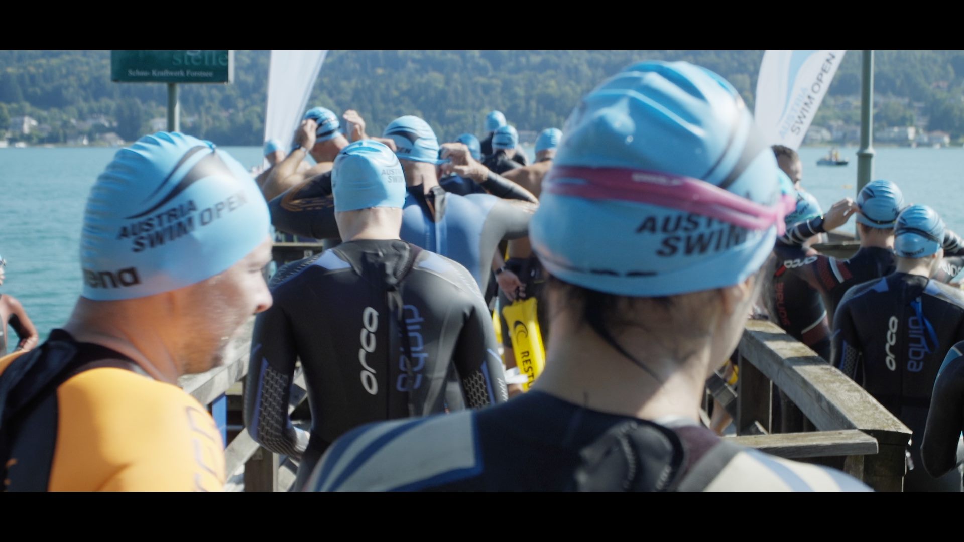 Eine Gruppe von Menschen in Neoprenanzügen, die an den Austria Swim Open teilnehmen, steht auf einem Dock.