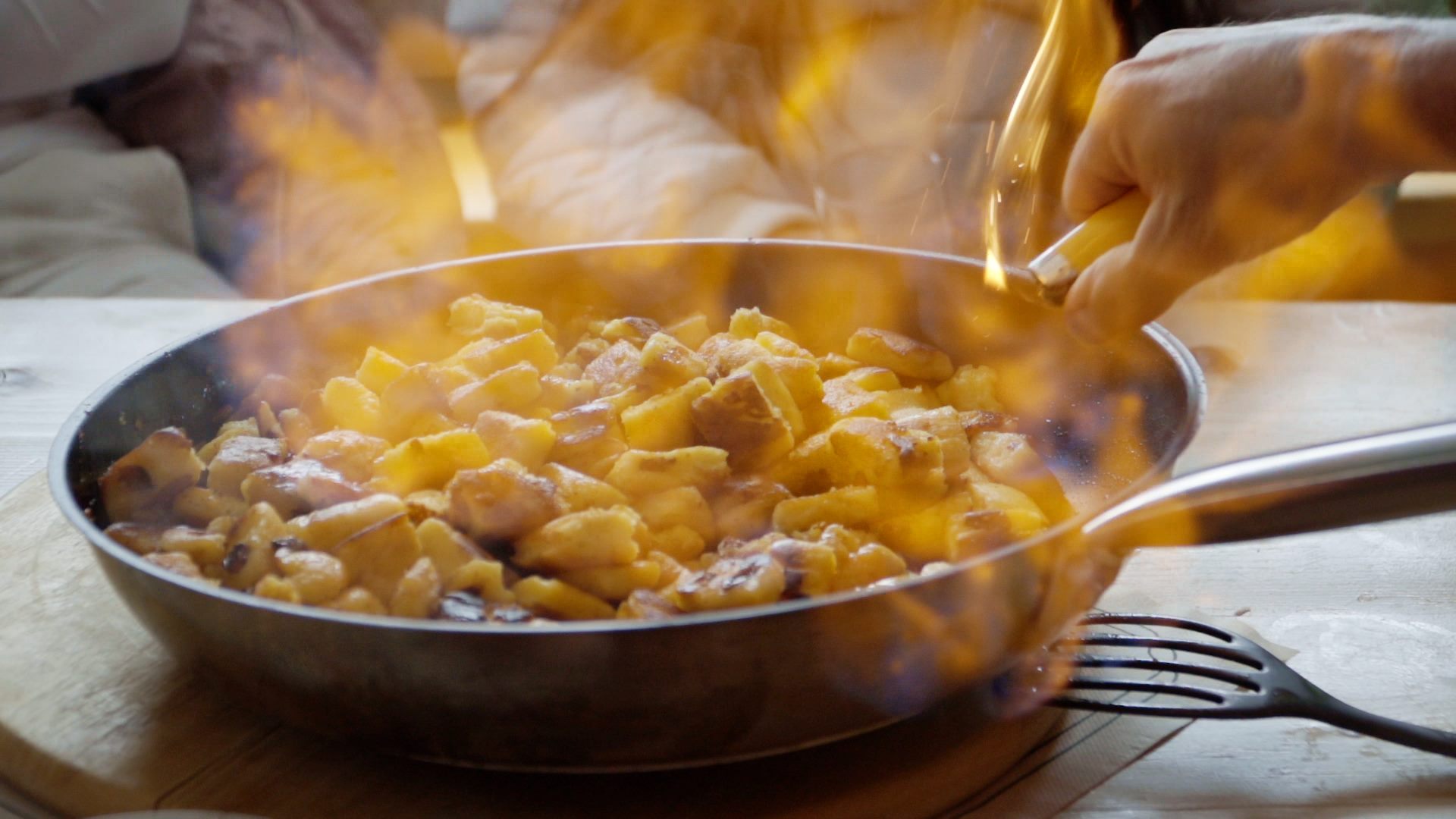 A person is frying potatoes in a pan at a residence in the Alps.
