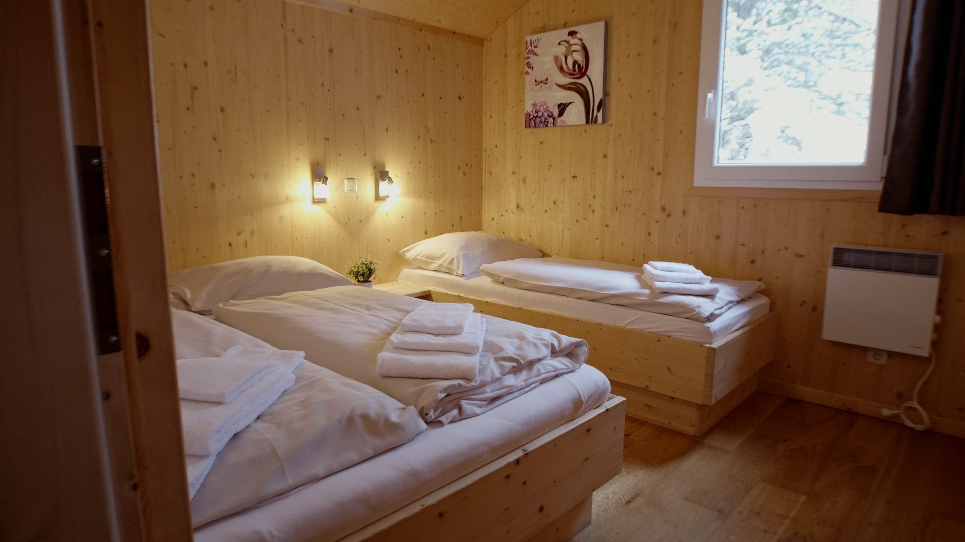 Zwei Betten in einem Zimmer mit Holzwänden in der Alps Residence.