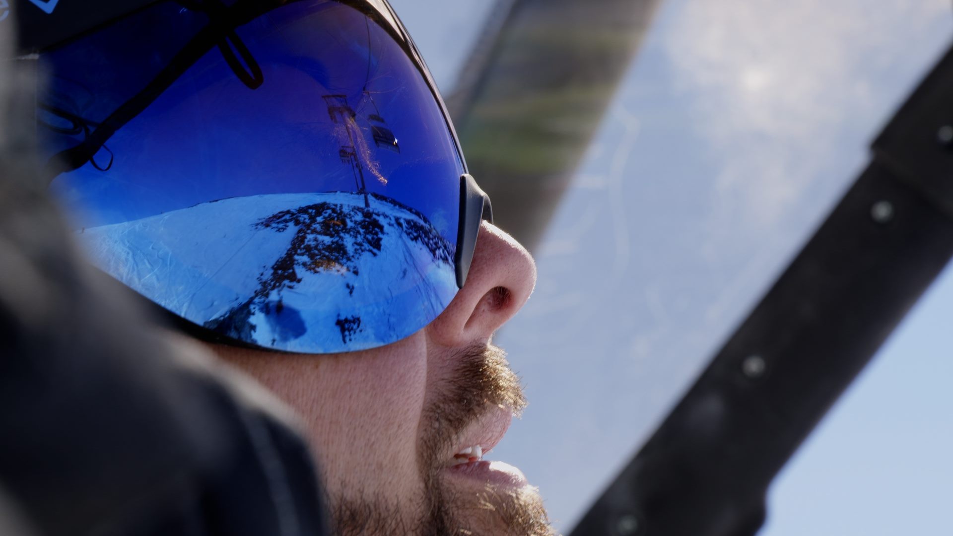 Ein Mann mit Skibrille blickt auf einen Alpenberg.