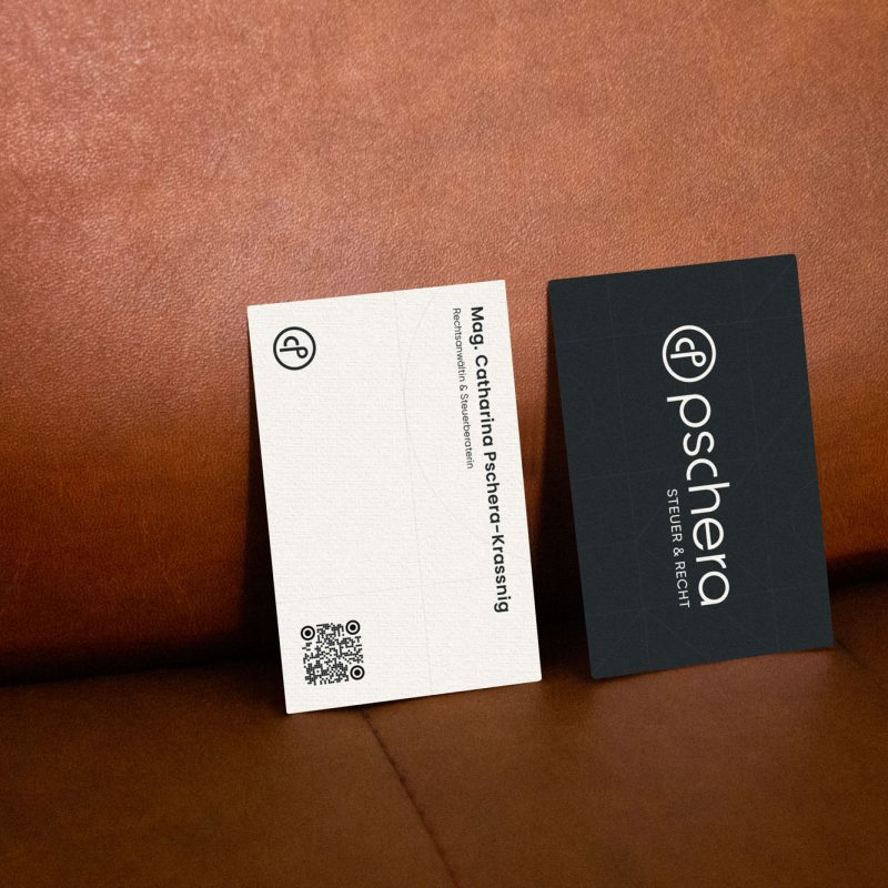 Two business cards displaying PMT company information sitting on a leather couch.