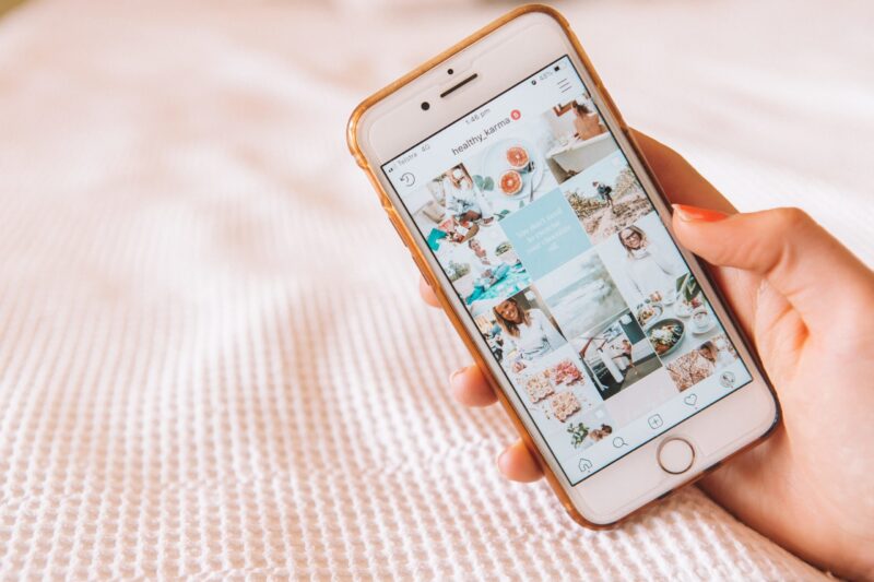 Eine Person hält ein iPhone mit Bildern darauf und präsentiert Designideen für die Planung und Erstellung eines ästhetisch ansprechenden Instagram-Feeds.