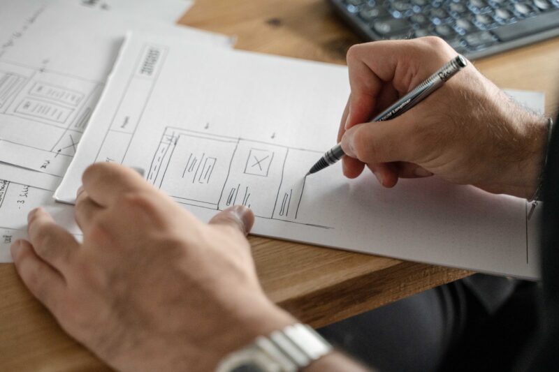 A person writing on a piece of paper with a pen.