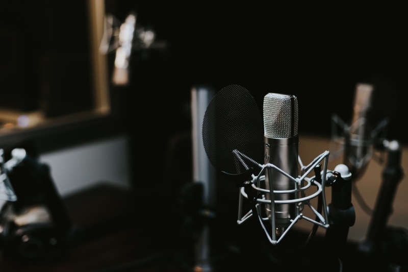 Auf einem Tisch in einem Aufnahmestudio steht ein Mikrofon, bereit für Podcasts.