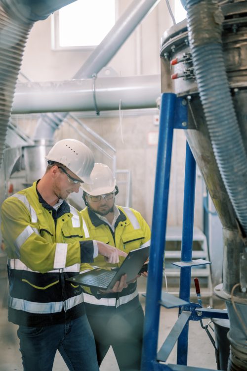 Two construction workers examining a document in a factory.