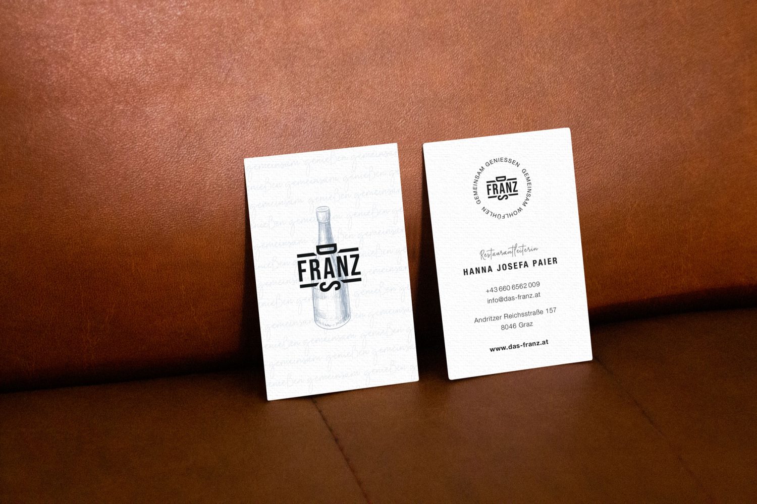 Two business cards on a leather couch.