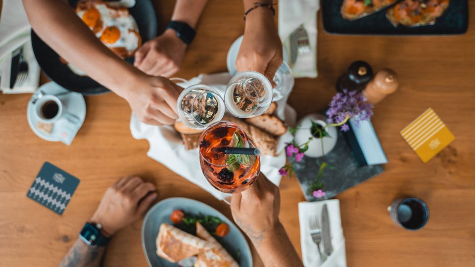 Eine Gruppe von Menschen stößt an einem Tisch mit Speisen und Getränken an und feiert im Das Franz.