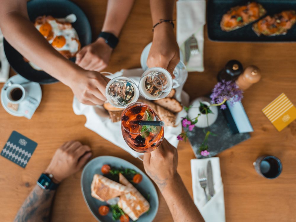 Eine Gruppe von Menschen stößt an einem Tisch mit Speisen und Getränken an und feiert im Das Franz.