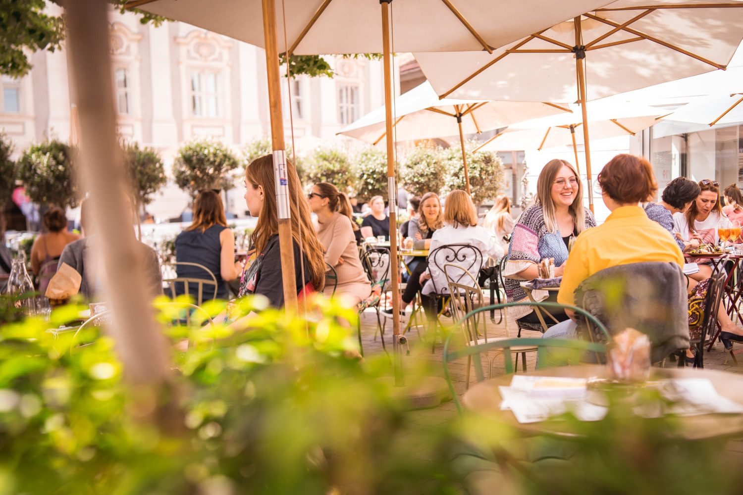 Menschen sitzen an Tischen in einem Kunsthauscafé im Freien.