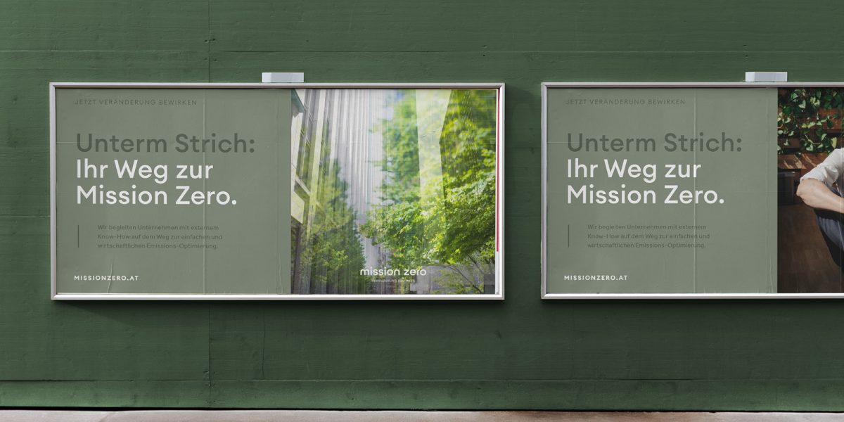 Zwei Werbetafeln, die für Mission Zero werben, an der Seite einer grünen Wand.