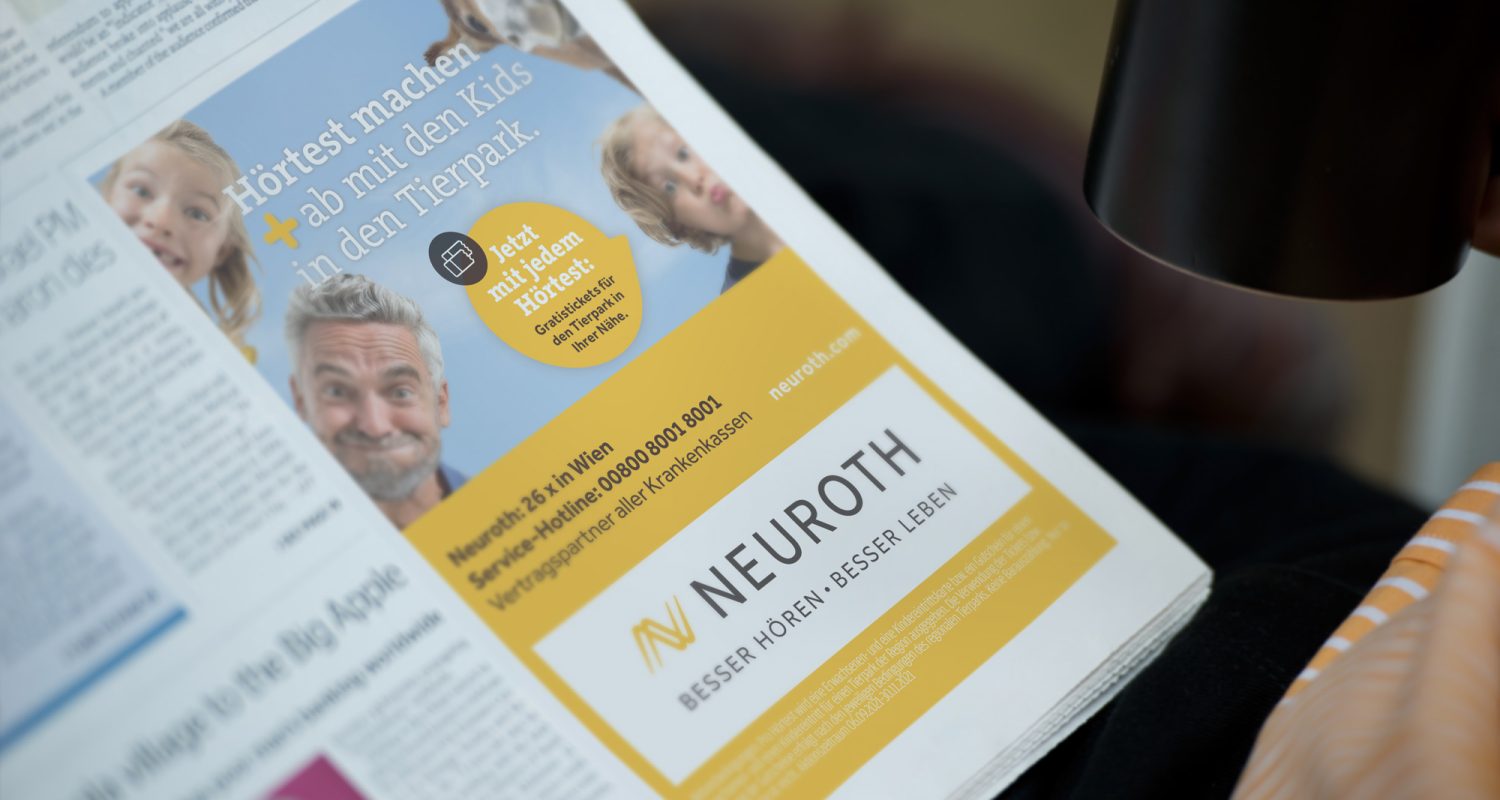 A man is reading a newspaper advertisement for Neuroth hearing aids.