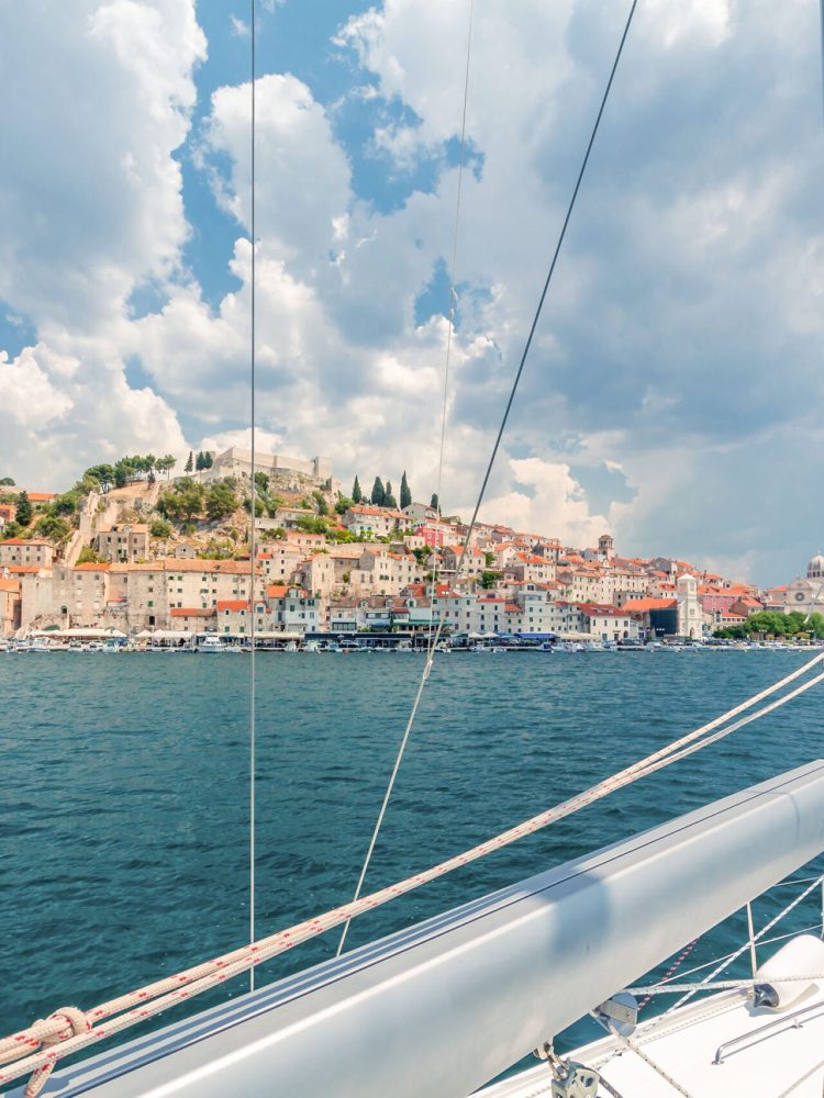 A view of a city from the deck of a sailboat.