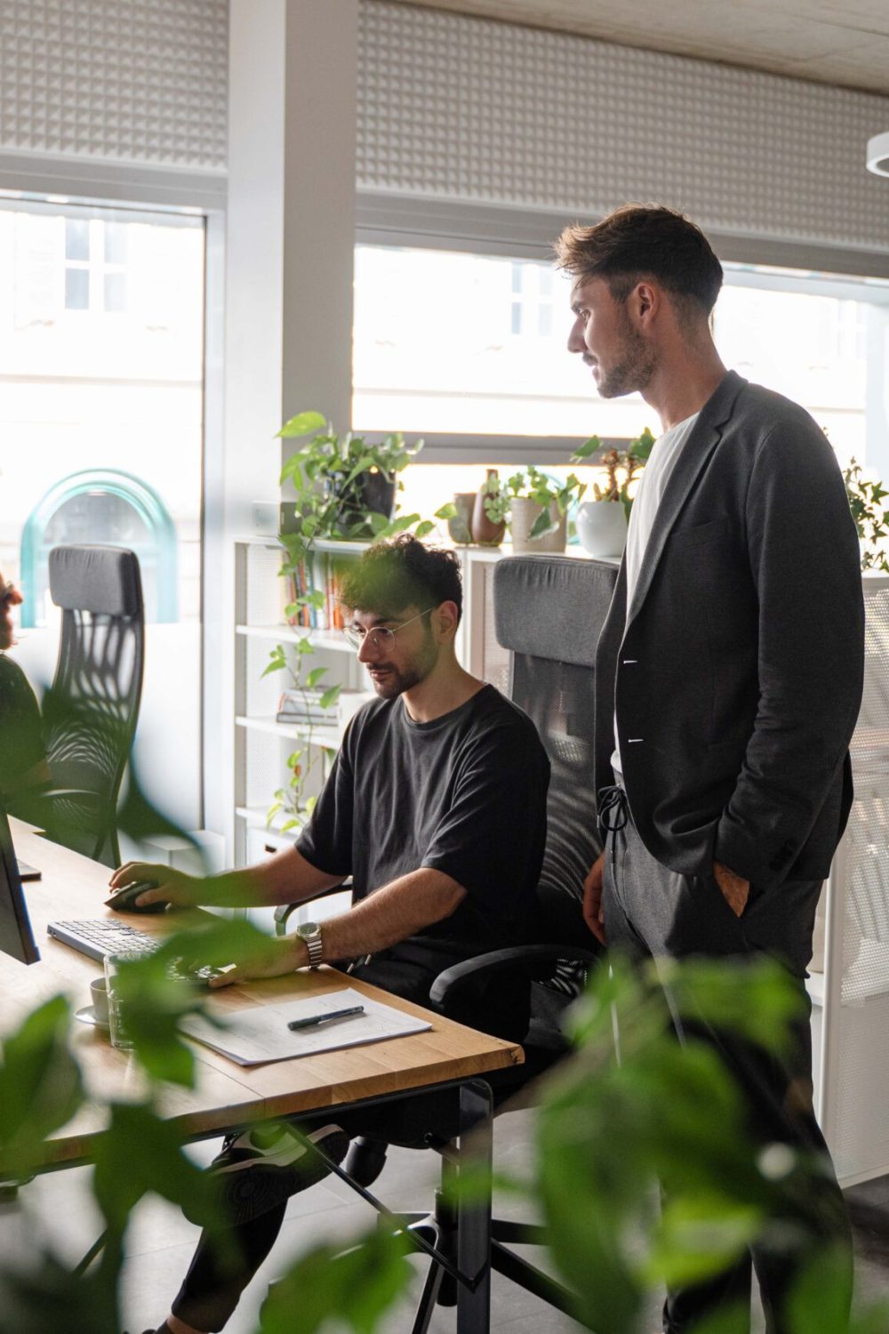 A group of people working in an office with plants.