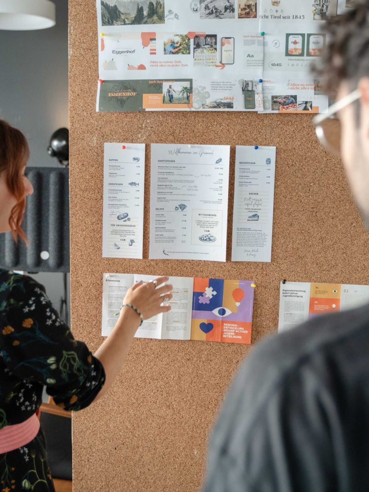 A woman and a man looking at a bulletin board.