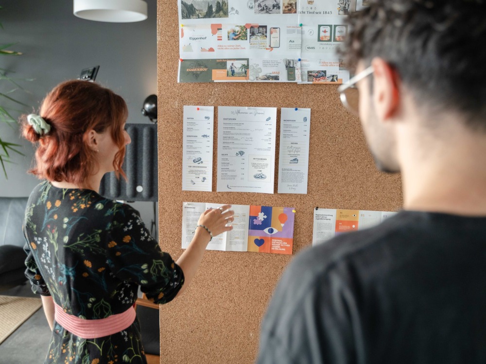 A woman and a man looking at a bulletin board.