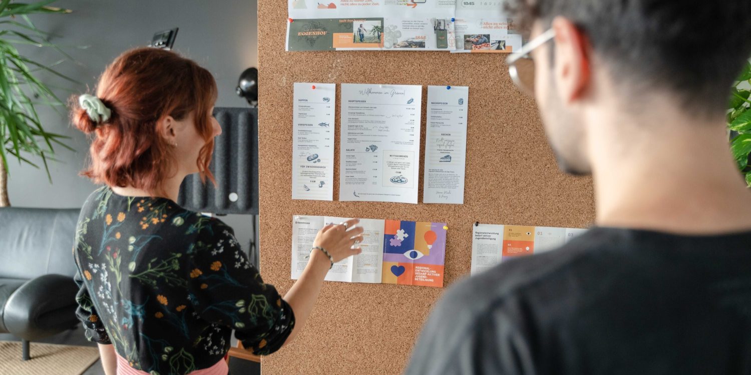 A woman and a man looking at a bulletin board.