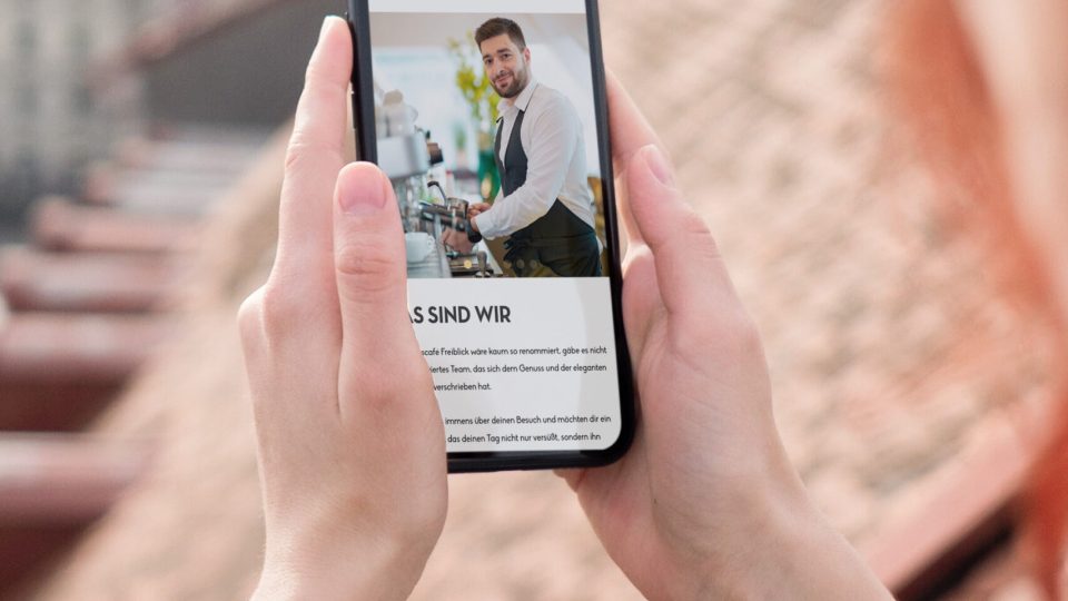 Eine Frau macht mit ihrem Handy ein Foto vom Restaurant Freiblick.