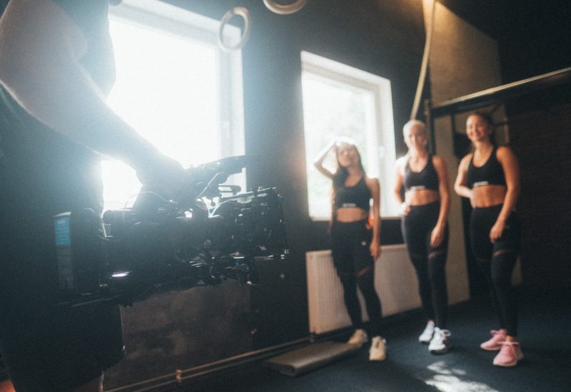 Eine Gruppe von Frauen steht in einem Fitnessstudio vor einer Kamera.