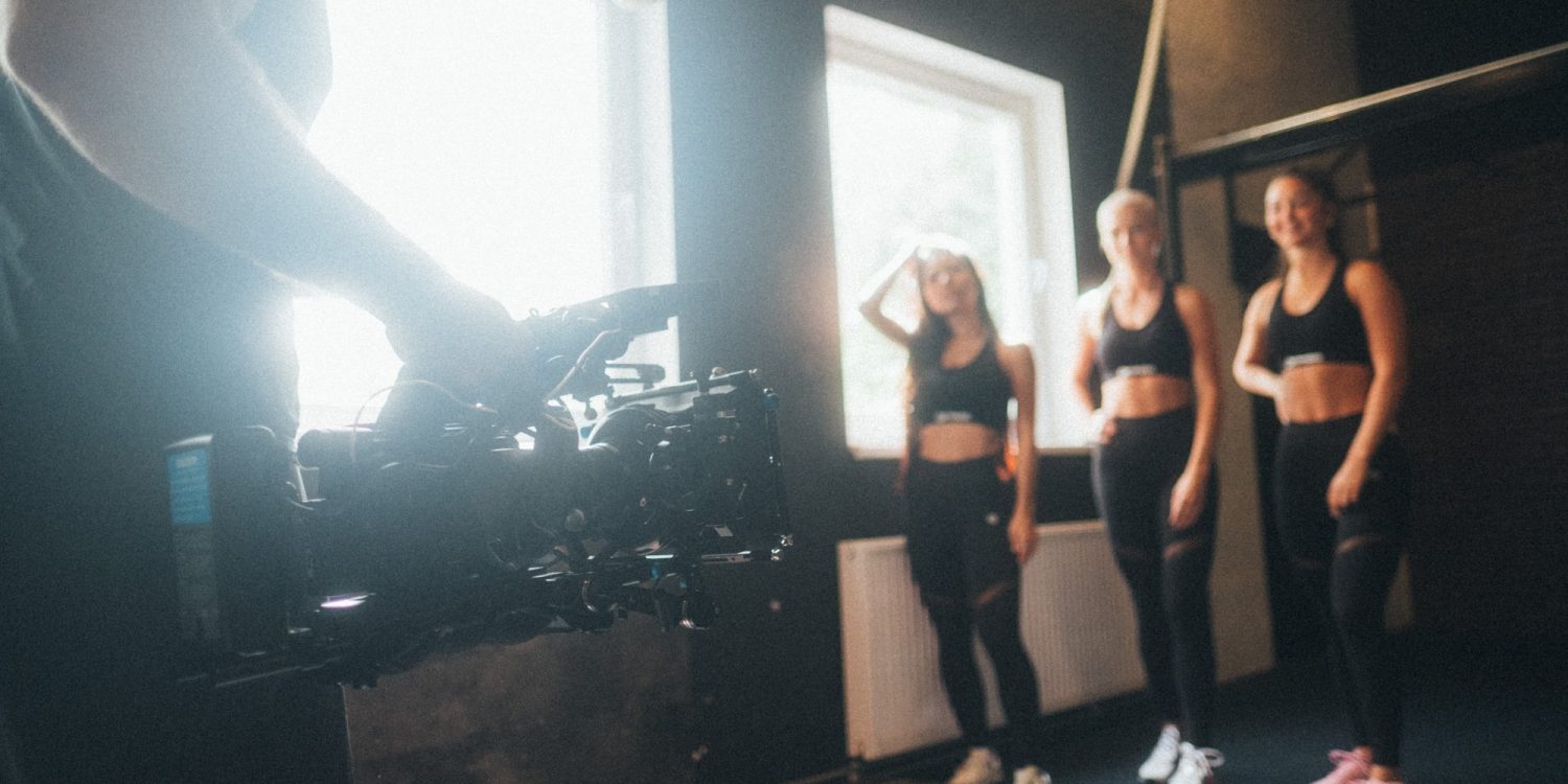 A group of women standing in front of a camera in a gym.